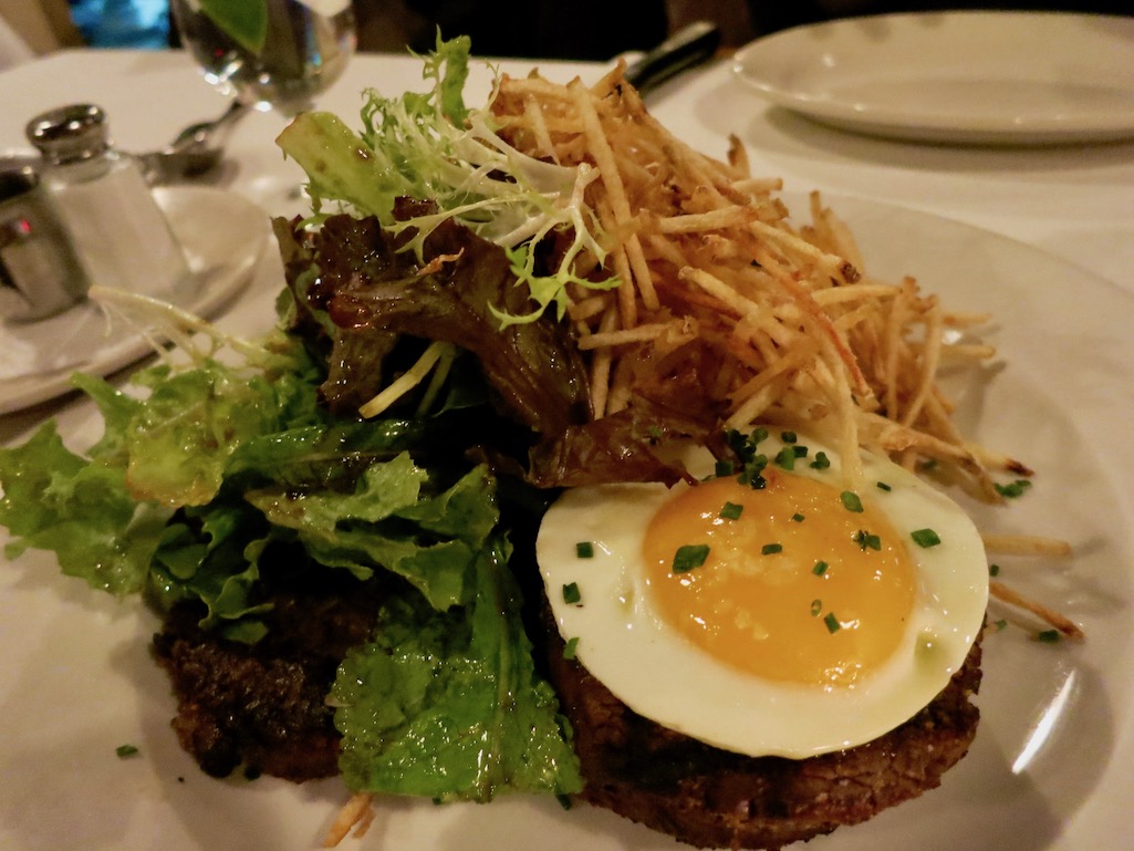 Bacaros Steak topped with egg served with side salad and shoe string potatoes in Providence Rhode Island